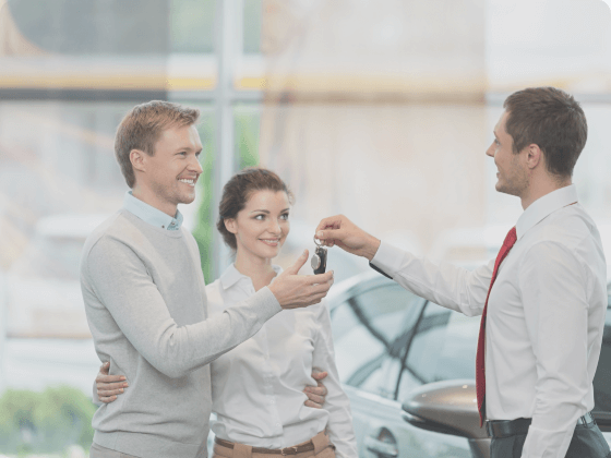 This image shows a man and woman being handed the keys to their new vehicle.